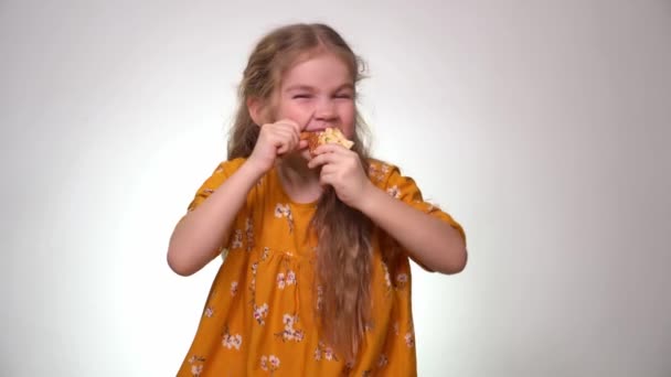 Маленькая девочка откусывает большой кусок пиццы и ест — стоковое видео