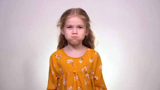 A little girl puffs out her cheeks and slaps them with her hands — Stockvideo