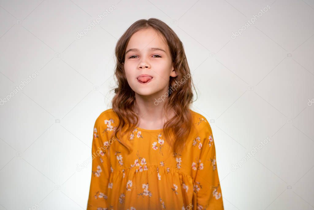 A teenage girl shows her tongue in an orange dress