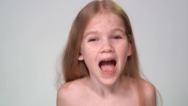 Smiling, little girl with freckles looks camera — Stockvideo