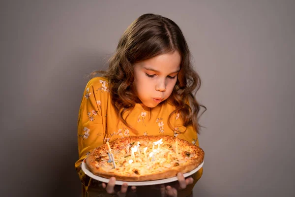 Een tiener meisje blaast kaarsen uit op de pizza verjaardag — Stockfoto