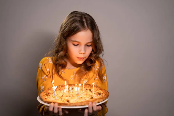 Tiener meisje blaast kaarsen op de pizza verjaardag — Stockfoto