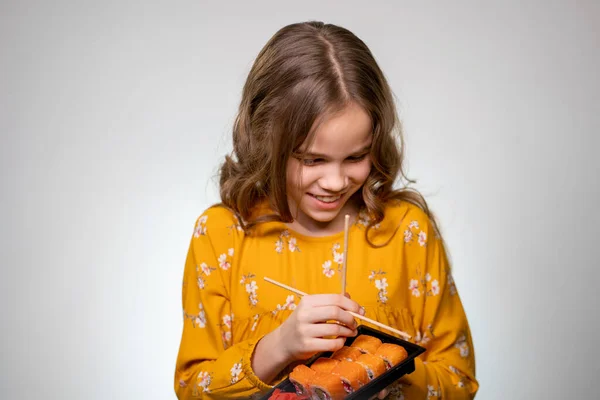 Teen girl learns how to hold chopsticks for sushi — Stockfoto