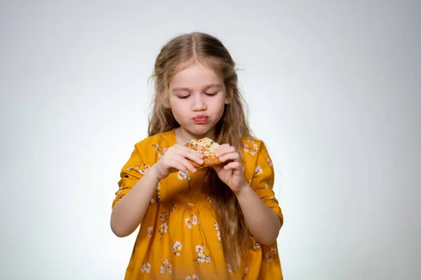 Das kleine Mädchen beißt lachend in die Pizza. — Stockfoto