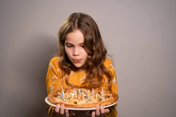 Teenie-Mädchen pustet Kerzen an Pizza-Geburtstag aus — Stockfoto