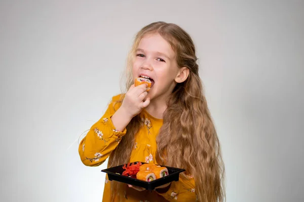 Little girl bites tasty rolls and holds in hands. — Stockfoto