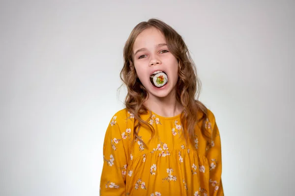 Girl puts roll in his mouth and looking at camera. — Stockfoto