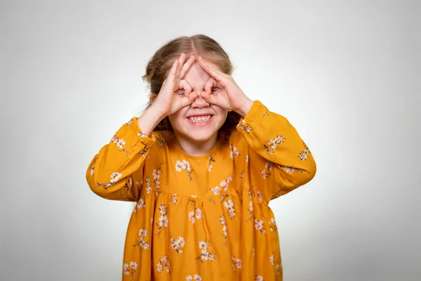 Finger glasses make a little girl blonde funny — Stockfoto