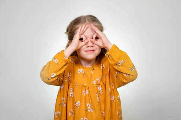 Finger glasses make a little girl blonde funny — Stockfoto