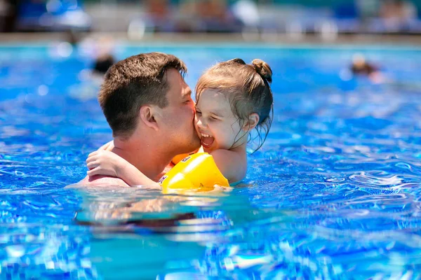 Papá e hija juegan y se abrazan en la piscina . — Foto de Stock