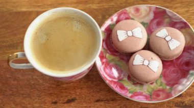 Cup coffee and macaroons, hand takes, gets bitten.