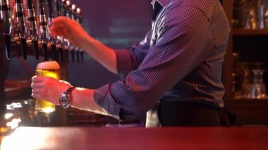 Barmen fıçıdan bira doldurur ve masaya koyar. 