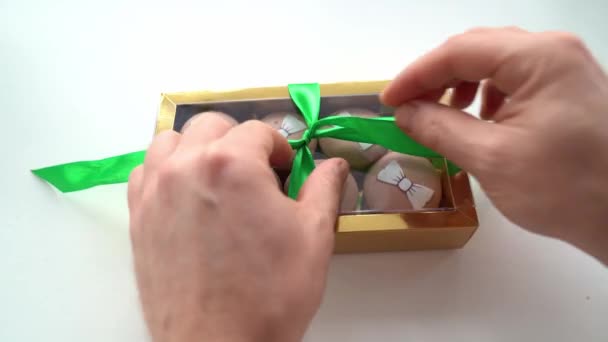 Untying the green bow on gold box with macaroons. — Stock Video