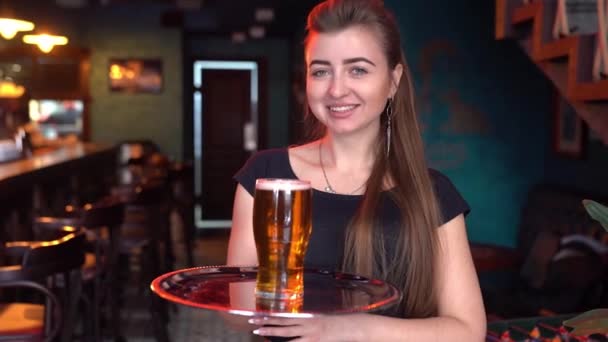 Улыбающаяся официантка держит поднос полный бокал пива — стоковое видео