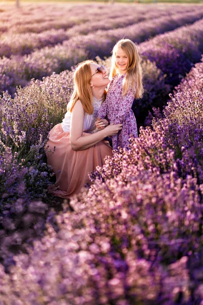 Moeder met dochter in lavendelveld bij zonsondergang. — Stockfoto