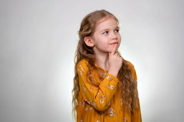 Het kleine meisje houdt de vinger naar een gezichtsmeisje en denkt: — Stockfoto