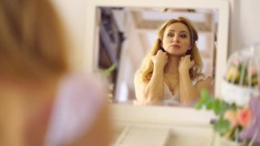 Sarışın kız aynanın karşısına oturur, kendisine bakar.