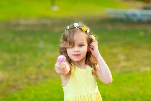 Petite fille en couronne tend la main avec une fleur — Photo