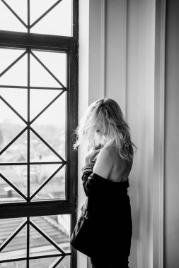 Siyah elbiseli sarışın kız açık omuzlu, topuklu.