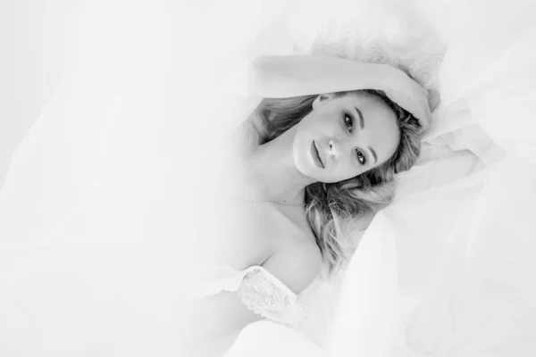 Une fille blonde en sous-vêtements blancs est allongée sur le lit — Photo