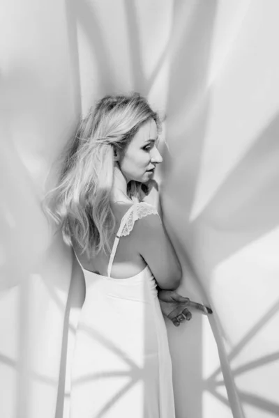 Blond flicka i en vit klänning på en vit bakgrund — Stockfoto