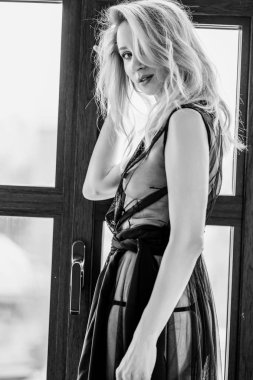 Pencerenin yanında siyah gecelikli sarışın bir kız.