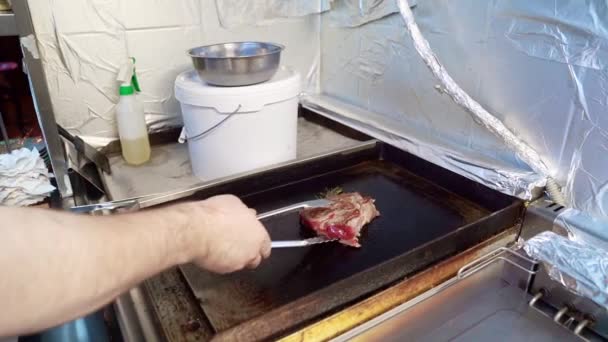 Повар переворачивает кусок мяса на плите . — стоковое видео