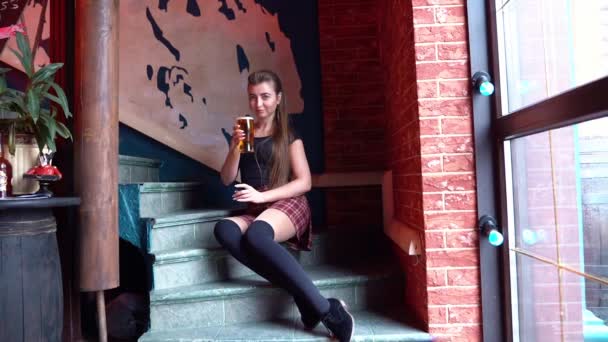 Girl sitting on the steps drinking beer from glass — Αρχείο Βίντεο