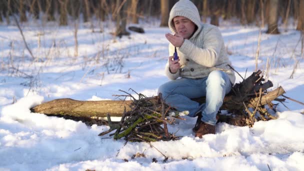 Un hombre enciende un encendedor en el bosque de invierno — Vídeos de Stock