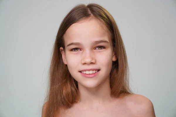 Tonåring flicka med blont hår leende en vit vägg — Stockfoto