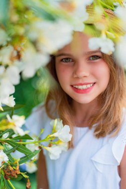 Portrait of blonde girl in hat among white flowers