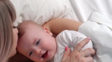 the baby is lying with mom in bed and naughty