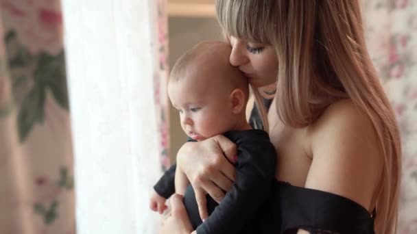 Mother and child in black clothes stand at window — Stok video