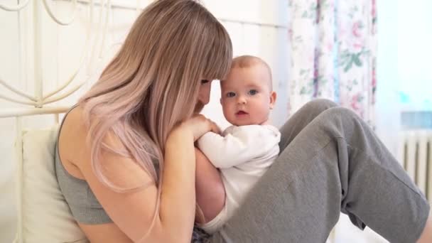 Mamá con el bebé sentado en la cama en casa — Vídeos de Stock