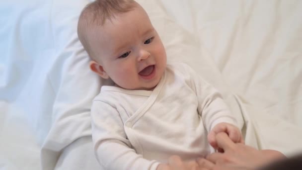Tickling. baby is lying on mum feet and looks up — Stockvideo