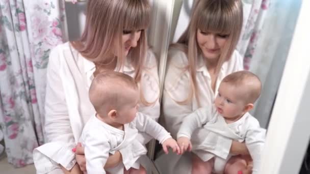 Una madre con un bebé se mira en el espejo en el dormitorio — Vídeos de Stock