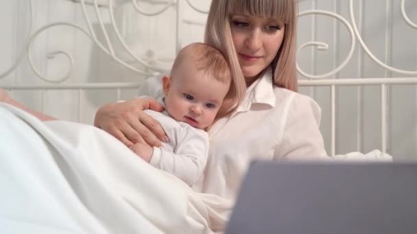 Мать в постели с ребенком, работающей с компьютером . — стоковое видео