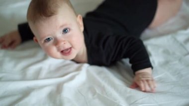 kid in black clothes lying on paunch on white bed