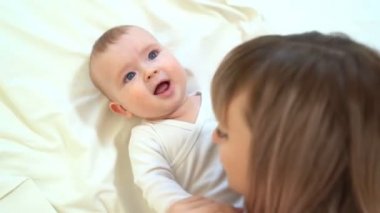 mum and son lying on bed. baby learns to crawl.