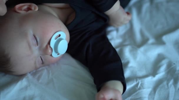 Kid in black clothes with pacifier in mouth sleep — Stock video