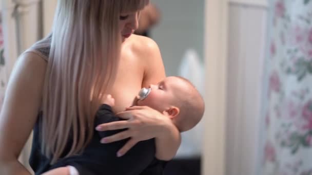 Mom in black cradles baby with a pacifier in mouth — Stockvideo