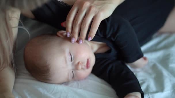 The mother stroking the head of a sleeping baby — Stockvideo