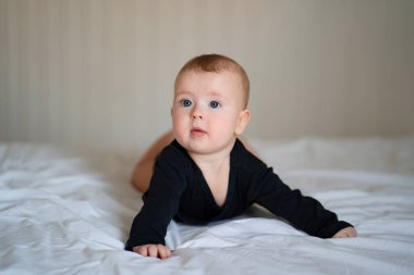 kid in black clothes lying on paunch on white bed