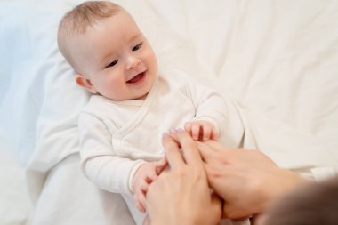 Beyaz elbiseli çocuk yatakta sırt üstü yatıyor.
