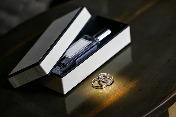 Anillos de boda y una caja con una botella de perfume — Foto de Stock
