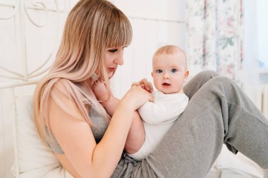 mom sitting on bed with baby and playing with son