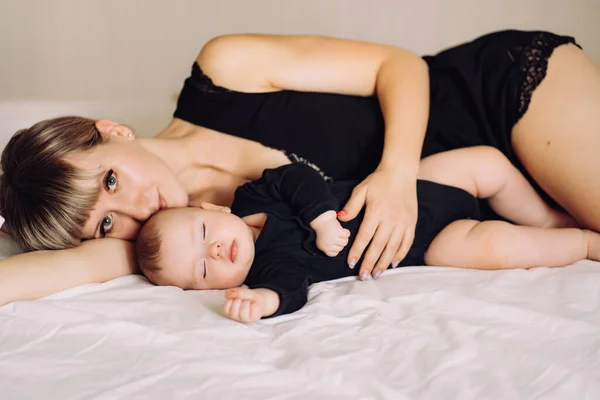 Mama și copilul în negru dormind împreună pe pat — Fotografie, imagine de stoc