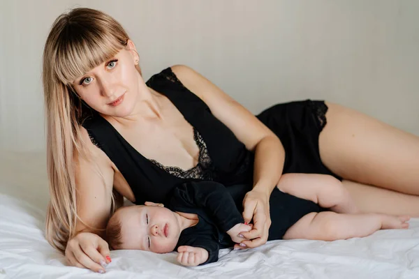 Mom and baby  in black lying together on bed — 图库照片