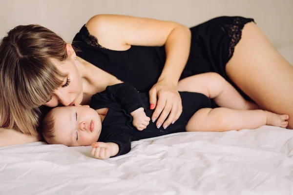 Madre y bebé acostados juntos en la cama, besándose hijo —  Fotos de Stock