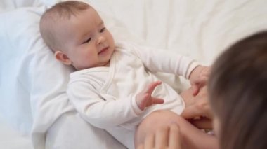 baby is lying on mum feet and looks up